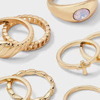 Gold-tone cross and sun ring set with rhinestone details displayed on a warm surface