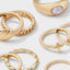 Gold-tone cross and sun ring set with rhinestone details displayed on a warm surface