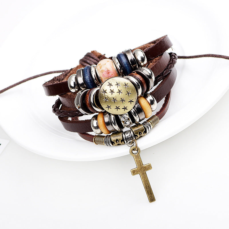 Close-up of cross pendant on braided leather wristband