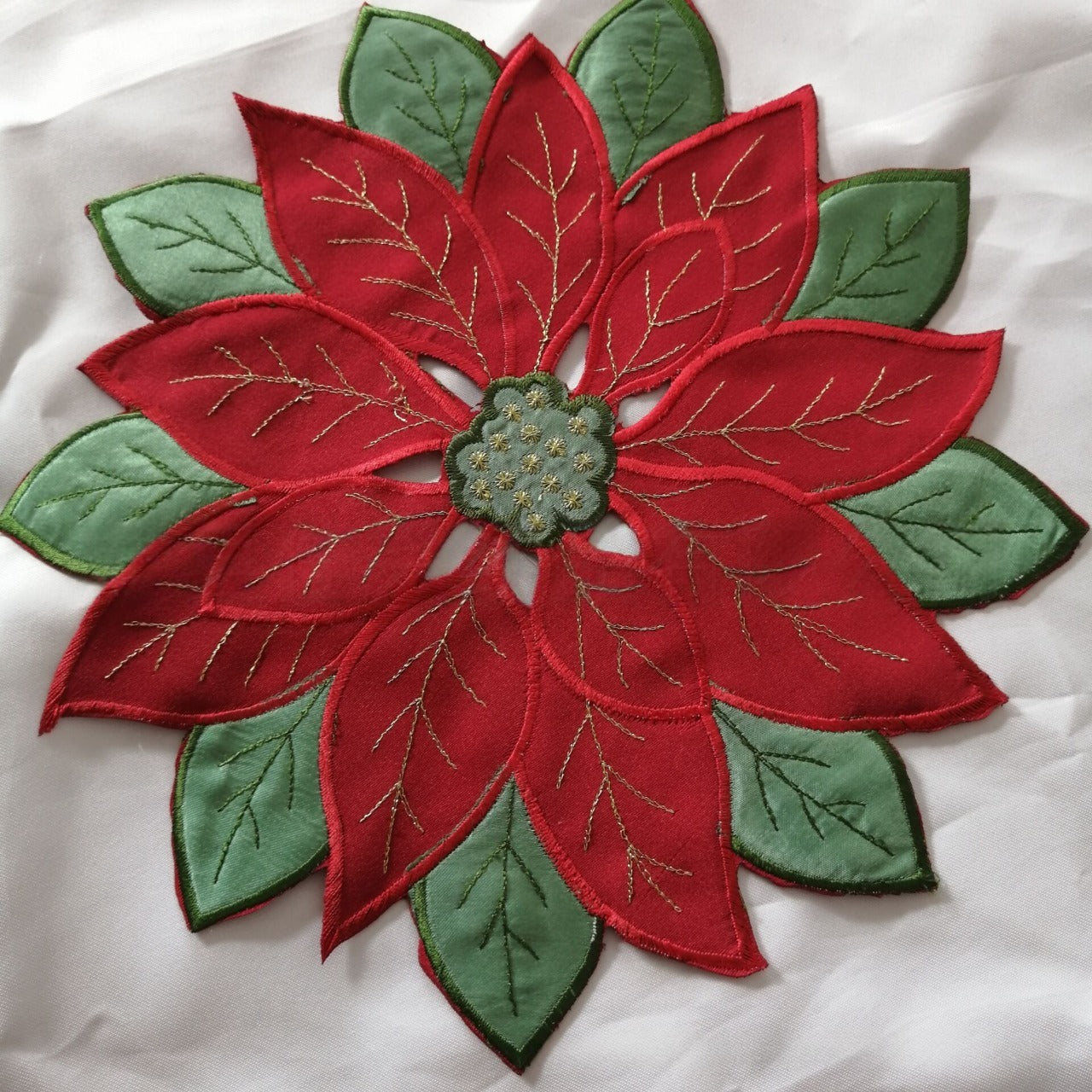 Embroidered Christmas tablecloth with leaf pattern in red and green on dining table