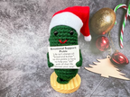 Green plush Christmas gift with base, featuring soft fabric texture and cozy holiday colors