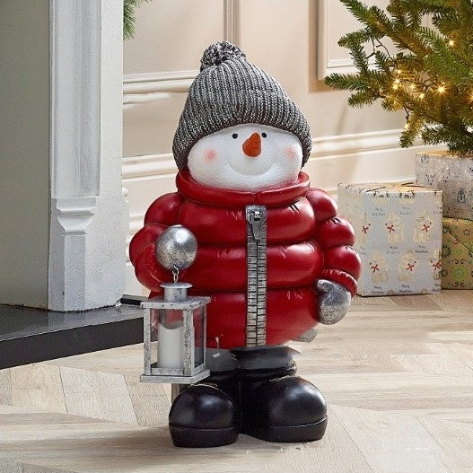 Cheerful snowman Christmas ornament wearing red down jacket and scarf for holiday tree