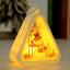 Retro white Christmas candle lamp ornament glowing warmly on wooden surface
