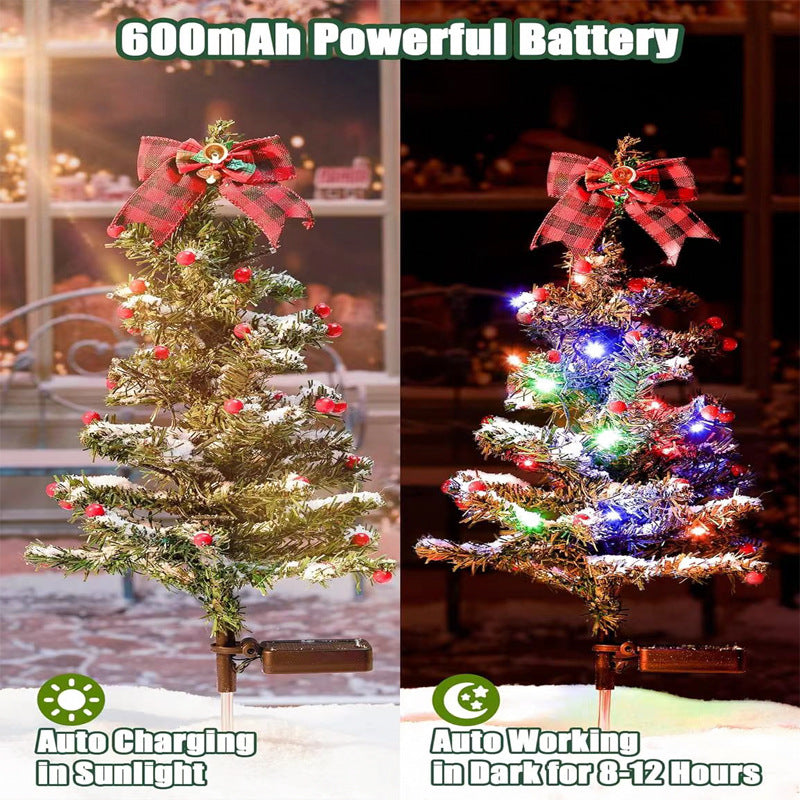 Two-pack of solar Christmas tree stake lights standing in a snowy front yard pathway at dusk