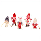Wooden ski doll ornament in white clothes with grey hat next to Christmas greenery