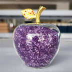Crystal apple ornament hanging among holiday greenery