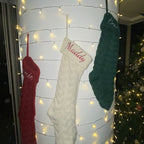 Red embroidered knitted Christmas stocking gift bag displayed at holiday gathering