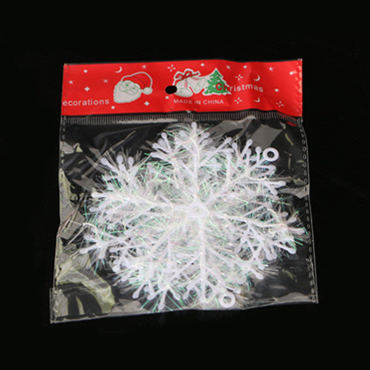 Brushed plastic snowflake ornament hanging on Christmas tree with red ribbon