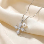 White pearl charm hanging beside a polished silver cross pendant