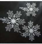 Transparent acrylic snowflake pendant hanging on a Christmas tree with red and green ornaments