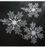 Transparent acrylic snowflake pendant hanging on a Christmas tree with red and green ornaments