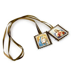 Cloth pendant and ruler showing the 4 by 3 centimeter size of the ornament